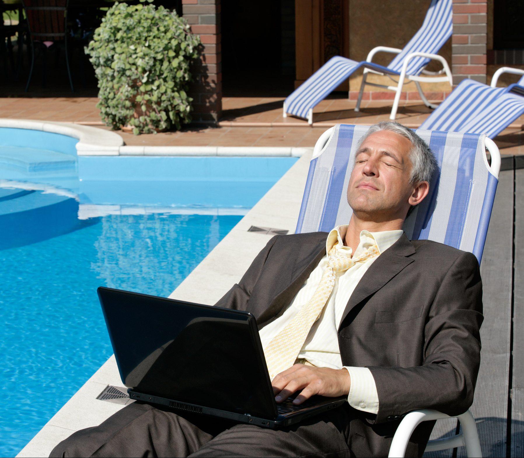 Businessman with laptop computer resting on deckchair